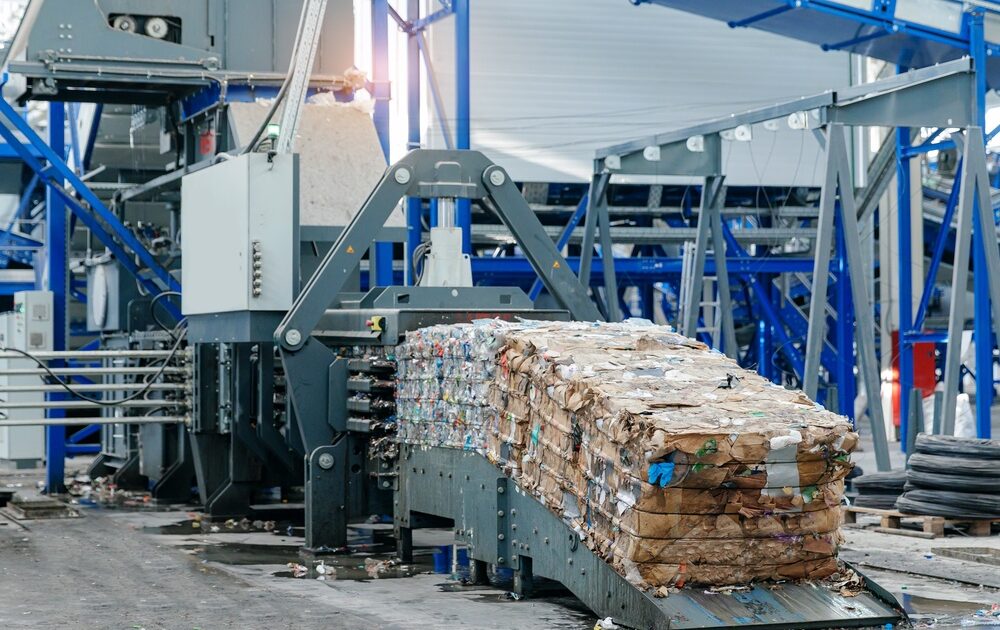 Recycling plant machinery compressing sorted waste into bales.